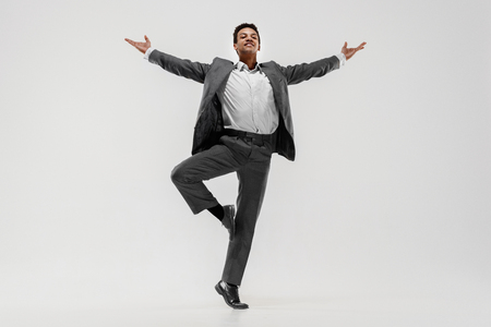 Happy businessman dancing in motion isolated on white studio background. Flexibility and grace in business. Human emotions concept. Office, success, professional, happiness, expression conceptsの写真素材