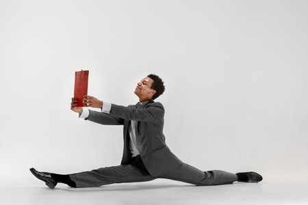 Happy businessman dancing in motion isolated on white studio background. Flexibility and grace in business. Human emotions concept. Office, success, professional, happiness, expression conceptsの写真素材