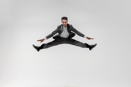 Happy businessman dancing in motion isolated on white studio background. Flexibility and grace in business. Human emotions concept. Office, success, professional, happiness, expression conceptsの写真素材