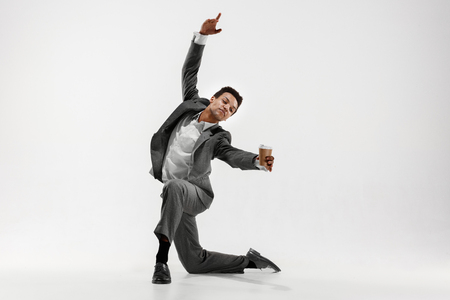 Happy businessman dancing in motion isolated on white studio background. Flexibility and grace in business. Human emotions concept. Office, success, professional, happiness, expression conceptsの写真素材