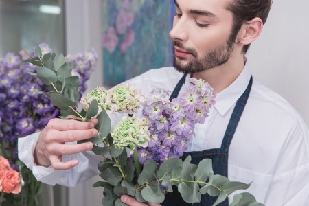 Small business. Male florist in flower shop. Floral design studio, making decorations and arrangements. Flowers delivery, creating order. The man in female profession. Gender equality conceptの写真素材