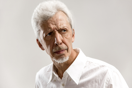 Serious businessman standing, looking at camera isolated on gray studio background. Male half-length...