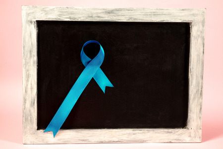 Colon cancer awareness poster. Blue ribbon on black board background. The health, awareness, help, care, support, hope, illness and healthcare conceptの写真素材