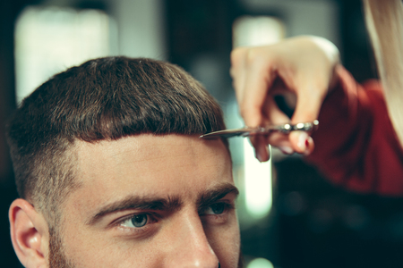 Client during beard shaving in barbershop. Female barber at salon. Gender equality. Woman in the male profession.の写真素材