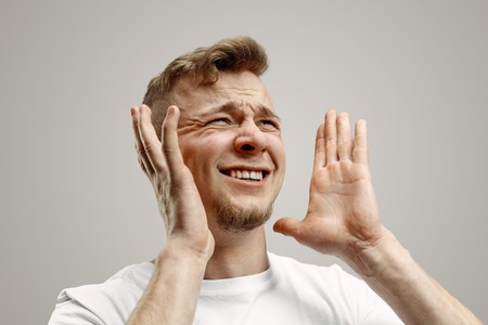 Why is that. Beautiful male half-length portrait isolated on gray studio backgroud. Young emotional...