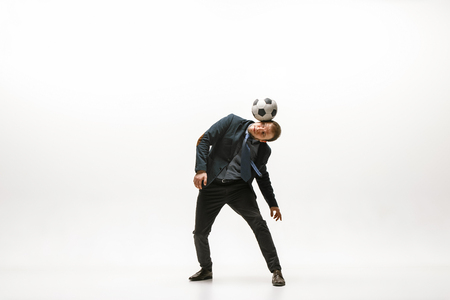 Businessman with football ball in office. Soccer freestyle. Concept of balance and agility in business. Manager perfoming tricks isolated on white studio background.の写真素材