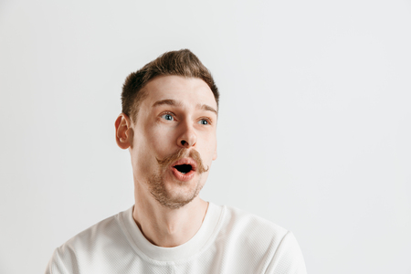 Wow. Attractive male half-length front portrait on gray studio backgroud. Young emotional surprised bearded man standing with open mouth. Human emotions, facial expression conceptの写真素材