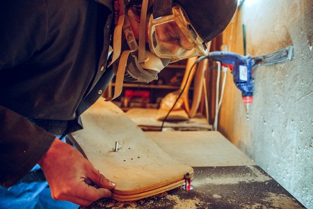 Portrait of handsome carpenter working with wooden skate at workshop, profile viewの写真素材