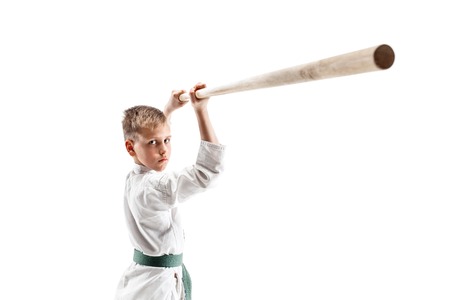 Teen boy fighting with wooden sword at Aikido training in martial arts school. Healthy lifestyle and sports concept. Fightrer in white kimono on white background. Karate man in uniform.の写真素材
