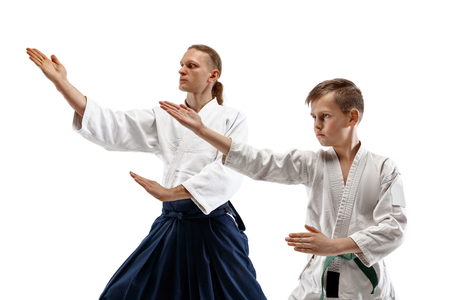 Man and teen boy fighting at Aikido training in martial arts school. Healthy lifestyle and sports concept. Fightrers in white kimono on white background. Karate men with concentrated faces in uniform.の写真素材