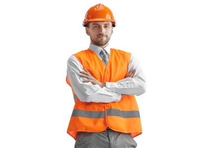 The builder in a construction vest and orange helmet standing on white studio background. Safety...