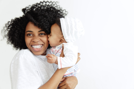 Closeup portrait of beautiful african woman holding on hands her little daughter on white background. Family, love, lifestyle, motherhood and tender moments concepts. Mothers day concept or backgroundの写真素材