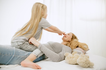 Young mother and her little daughter at home at sunny morning. Soft pastel colors. Happy family time on weekend. Mothers Day concept. Family, love, lifestyle, motherhood and tender moments concepts.の写真素材