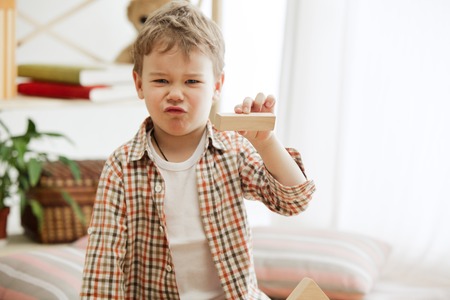 Little child sitting on the floor. Pretty boy palying with wooden cubes at home. Conceptual image...