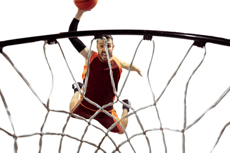 Full length portrait of a basketball player with ball isolated on white background. Advertising concept. Fit caucasian athlete jumping at studio and throwing the ball into the basketball hoop. Motion, activity, movement concepts.の写真素材