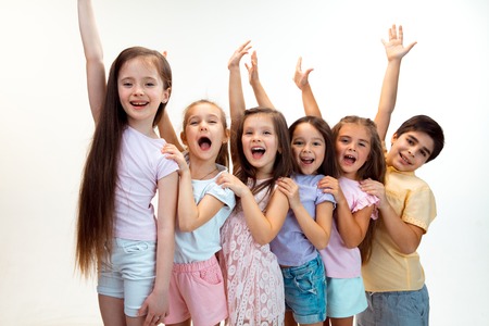 The portrait of happy cute little kids boy and girls in stylish casual clothes looking at camera against white studio wall. Kids fashion and human emotions conceptの写真素材