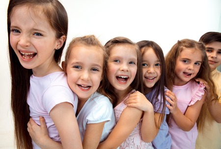 The portrait of happy cute little kids boy and girls in stylish casual clothes looking at camera against white studio wall. Kids fashion and human emotions conceptの写真素材