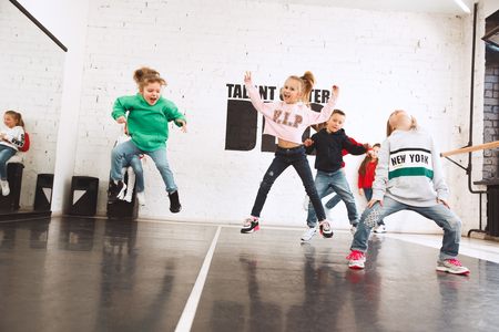 The kids at dance school. Ballet, hiphop, street, funky and modern dancers over studio background. Children showing aerobic element. Teens in hip hop style. Sport, fitness and lifestyle concept.の写真素材