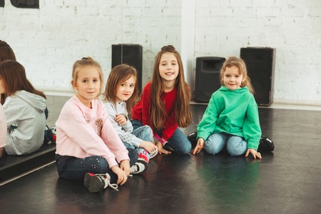 The kids sitting at dance school. Ballet, hiphop, street, funky and modern dancers concept. Studio background. Teens in hip hop style. Sport, fitness and lifestyle concept.の写真素材