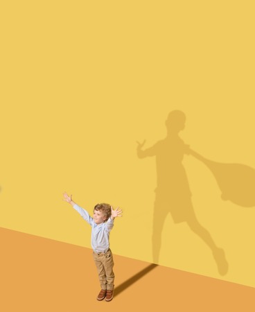 Ill promise to win in first time. Childhood and dream concept. Conceptual image with child and shadow on the yellow studio wall. Little boy want to become tennis player and to build a sport career.の写真素材