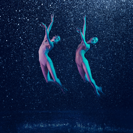 Birds. Two young female ballet dancers under water drops and spray. Caucasian and asian models...