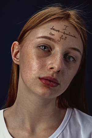 Portrait of young woman with mental health problems. The image of a tattoo on the forehead with the...