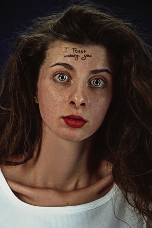 Portrait of young woman with mental health problems. The image of the tattoo on the forehead with...