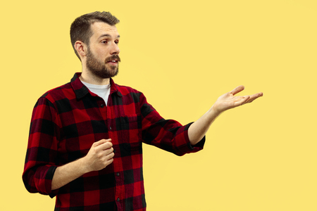 Half-length close up portrait of young man in shirt on yellow background. The human emotions, facial expression concept. Front view. Trendy colors. Negative space. Showing or pointing.の写真素材