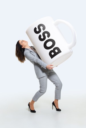 Responsibility. Young woman under pressure from the boss or cant cope with the duties of the head. Holding a big cup of coffee. Concept of office workers troubles, business, problems and stress.の写真素材