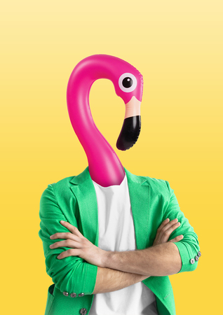 Male body in green jacket headed by a pink swim flamingo against yellow background. Negative space to insert your text. Modern design. Contemporary art collage. Vacation, summer, resort.の写真素材