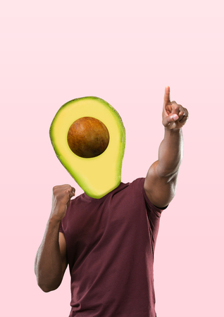 Male body in purple shirt headed by a green avocado and pointing against trendy coral background. Negative space to insert your text. Modern design. Contemporary art collage. Vacation, summer, resort.の写真素材