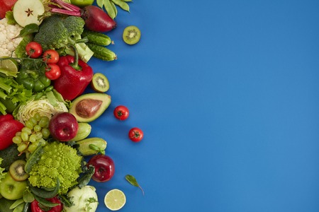 Healthy food dish on blue background. Healthful set including vegetables and fruits. Grape, apple, kiwi, pepper, lime, cabbage, zucchini, grapefruit, avocado. Proper nutrition or vegetarian menu.の写真素材