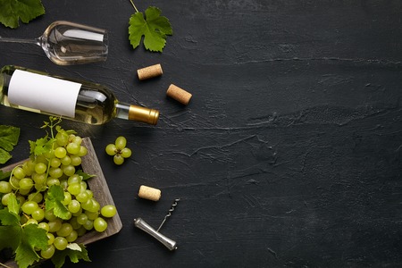 Top view of tasty fruit plate with the wine bottle and glasses on the black stone on a kitchen plate on the black stone background, top view, copy space. Gourmet food and drink.