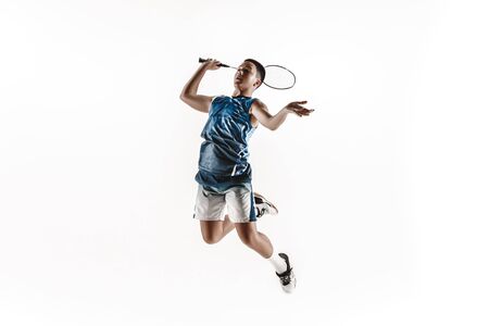 Little boy playing badminton isolated on white studio background. Young male model in sportwear and sneakers with the racket in action, motion in game. Concept of sport, movement, healthy lifestyle.の写真素材