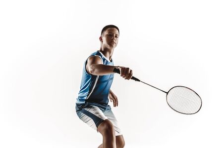 Little boy playing badminton isolated on white studio background. Young male model in sportwear and sneakers with the racket in action, motion in game. Concept of sport, movement, healthy lifestyle.の写真素材