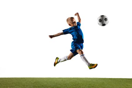 Young boy as a soccer or football player in sportwear making a feint or a kick with the ball for a goal on white studio background. Fit playing boy in action, movement, motion at game.の写真素材