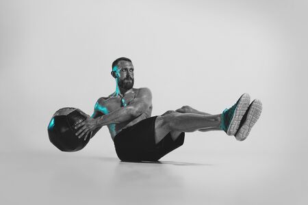 Self-building. Young caucasian bodybuilder training over studio background in neon light. Muscular...