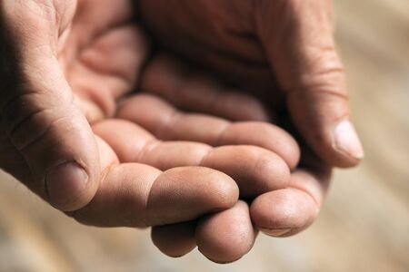 Male beggar hands seeking money, coins from human kindness on the wooden floor at public path way or street walkway. Homeless poor in the city. Problems with finance, place of residence.の写真素材