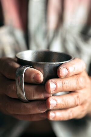 Male beggar hands seeking food or money with coins tin from human kindness on the wooden floor at public path way, street walkway. Homeless poor in the city. Problems with finance, place of residence.の写真素材