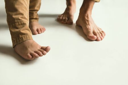 Familys legs on white studio background. Barefoot dad and son standing together. Concept fathers day...