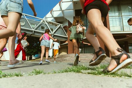 Happy kids playing at citys street in sunny summers day in front of modern building. Group of happy childrens or teenagers having fun together. Concept of friendship, childhood, summer, holidays.の写真素材