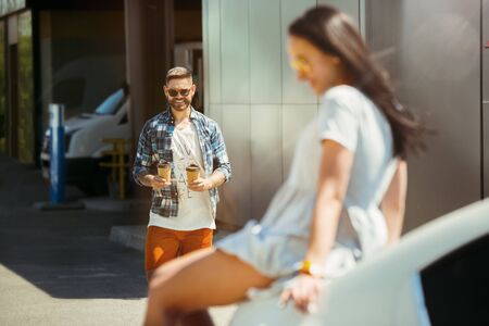 Young couple preparing for vacation trip on the car in sunny day. Woman and man shopping and ready...