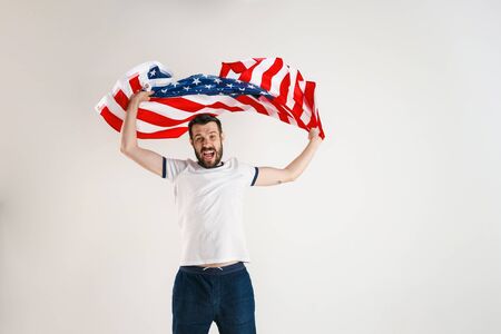 Celebrating an Independence day. Stars and Stripes. Young man with the flag of the United States of America isolated on white studio background. Looks crazy happy and proud as a patriot of his country.の写真素材