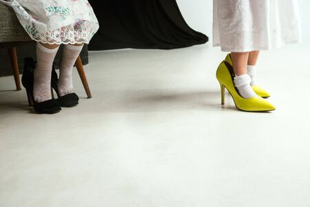 Interaction of children with adult world. Cute girls wearing mums oversize shoes and dress for being older like she is. Little female models trying on clothes at home. Childhood, style, dream concept.の写真素材