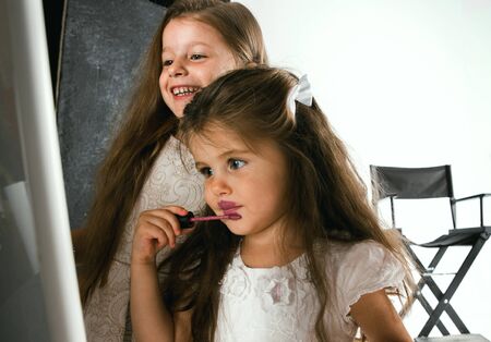 Interaction of children with adult world. Cute girls trying to do bright make up for being older....