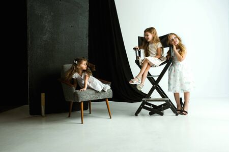 Interaction of children with adult world. Cute girls wearing mums oversize shoes and dress for being older like she is. Little female models trying on clothes at home. Childhood, style, dream concept.の写真素材