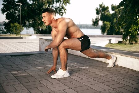 A muscular male athlete doing workout at the park. Gymnastics, training, fitness workout...