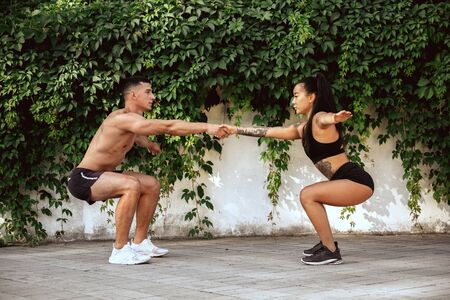 A muscular athletes doing workout at the park. Gymnastics, training, fitness workout flexibility....