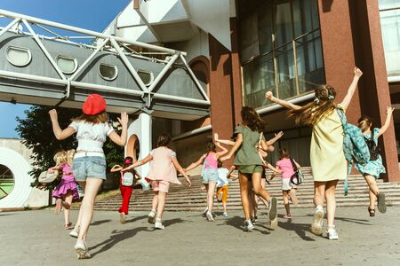 Happy kids playing at citys street in sunny summers day in front of modern building. Group of happy...