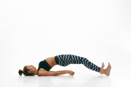 Sporty young woman doing yoga practice isolated on white studio background. Fit flexible female...